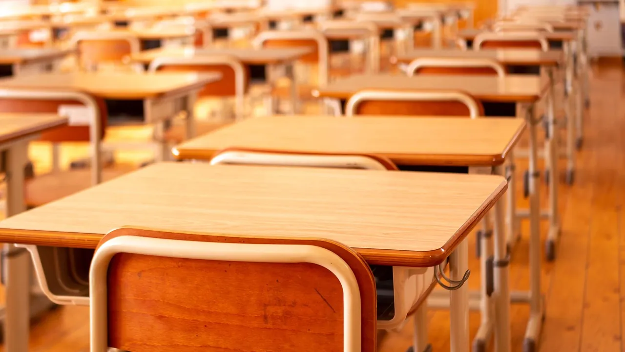 Pupitres d'écolier en bois alignés dans une salle vide