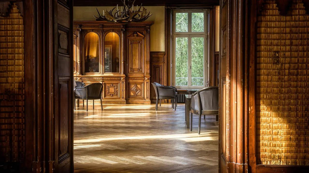 Salon lambrissé de bois avec des chaises disposées près des fenêtres