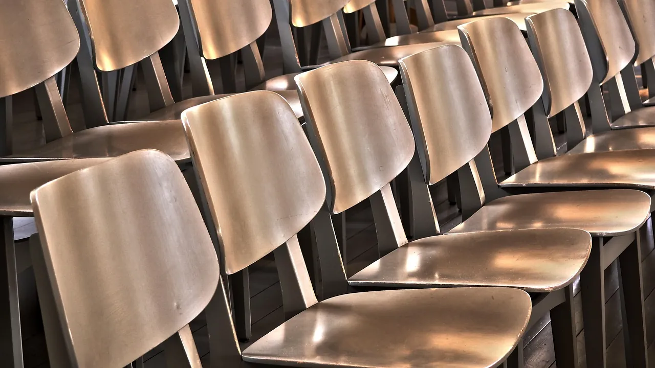 Rangée de chaises en bois vides dans une salle éclairée