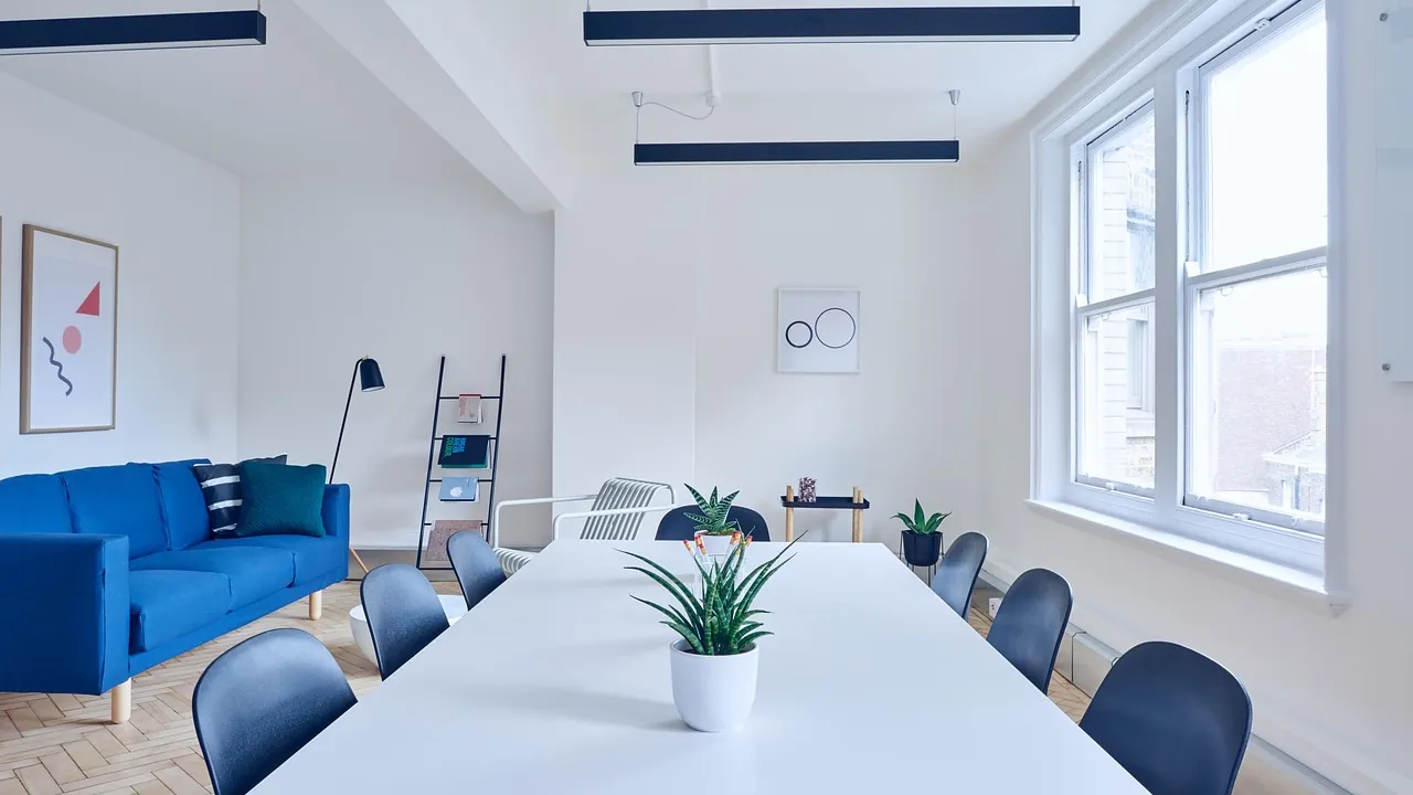 Salle de réunion claire avec une longue table blanche et un canapé bleu