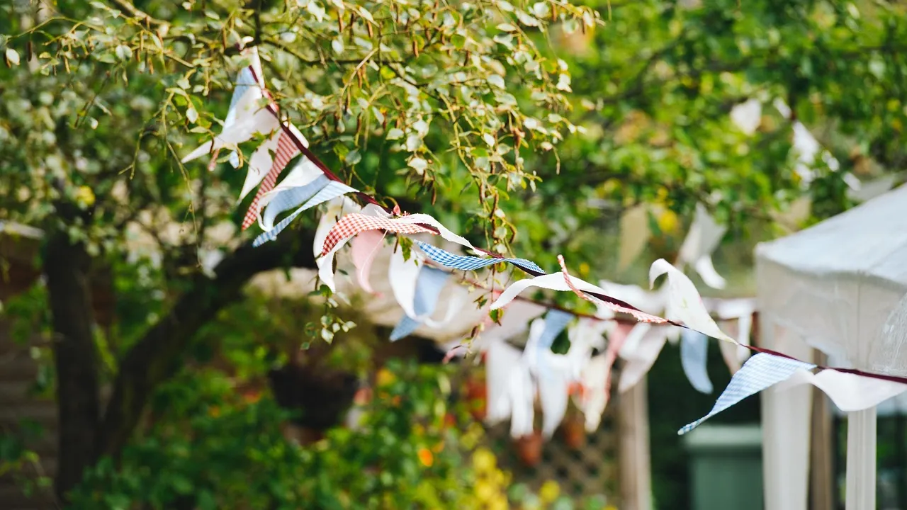 Guirlande de fanions tendue entre des arbres devant un chapiteau de jardin